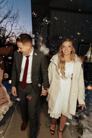 A couple in their wedding attire on their wedding day have a flash photography exit using a bubble machine. Photography by Hannah Lylene Photography.