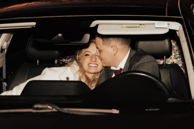 A couple in their wedding attire on their wedding day have a flash photography exit while in their car. Photography by Hannah Lylene Photography.