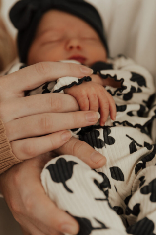 Details of a baby and mother holding hands in an indoor studio wearing neutral color matching outfits. Photography by Hannah Lylene Photography.