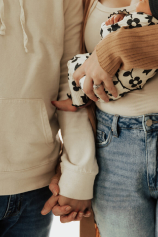 Close up shot of a young couple holds their newborn baby in an indoor studio wearing  neutral color matching outfits. Photography by Hannah Lylene Photography.