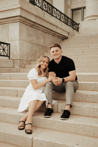 A couple in neutral attire in downtown Dallas Texas kiss and run around for engagement photos. Photography by Hannah Lylene Photography.