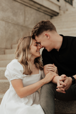 A couple in neutral attire in downtown Dallas Texas kiss and run around for engagement photos. Photography by Hannah Lylene Photography.