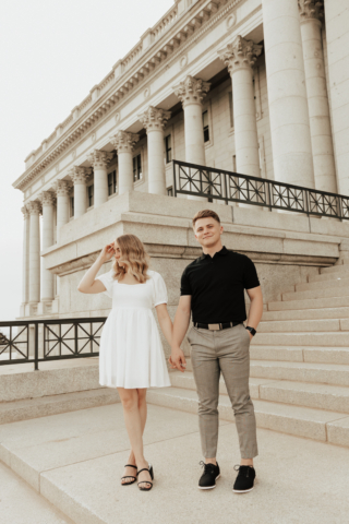 A couple in neutral attire in downtown Dallas Texas kiss and run around for engagement photos. Photography by Hannah Lylene Photography.