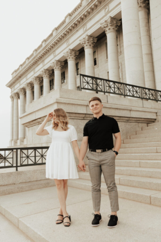 A couple in neutral attire in downtown Dallas Texas kiss and run around for engagement photos. Photography by Hannah Lylene Photography.