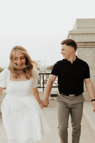 A couple in neutral attire in downtown Dallas Texas kiss and run around for engagement photos. Photography by Hannah Lylene Photography.