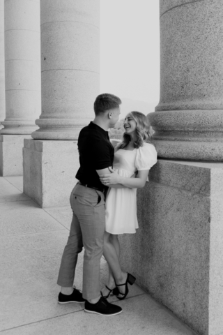 A couple in neutral attire in downtown Dallas Texas kiss and run around for engagement photos. Photography by Hannah Lylene Photography.