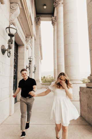 A couple in neutral attire in downtown Dallas Texas kiss and run around for engagement photos. Photography by Hannah Lylene Photography.