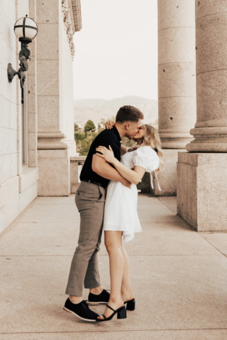 A couple in neutral attire in downtown Dallas Texas kiss and run around for engagement photos. Photography by Hannah Lylene Photography.