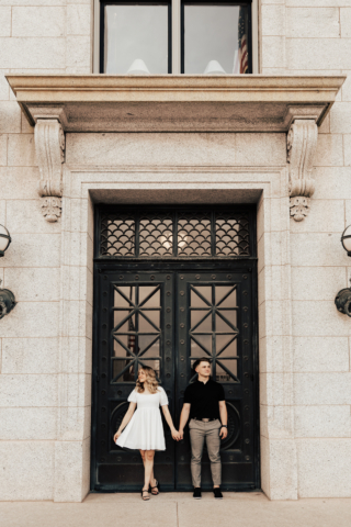 A couple in neutral attire in downtown Dallas Texas kiss and run around for engagement photos. Photography by Hannah Lylene Photography.