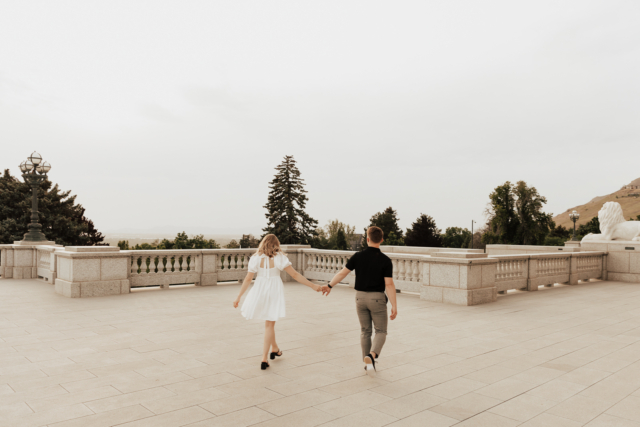 A couple in neutral attire in downtown Dallas Texas kiss and run around for engagement photos. Photography by Hannah Lylene Photography.