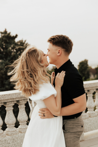 A couple in neutral attire in downtown Dallas Texas kiss and run around for engagement photos. Photography by Hannah Lylene Photography.