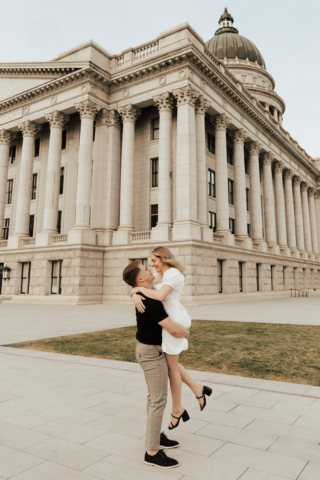 A couple in neutral attire in downtown Dallas Texas kiss and run around for engagement photos. Photography by Hannah Lylene Photography.