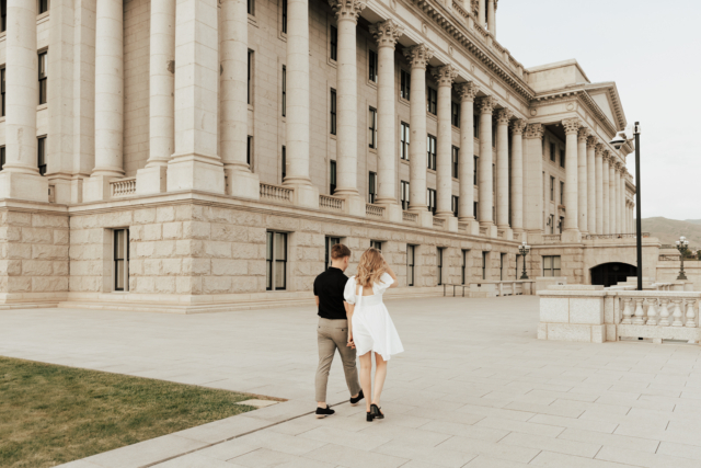 A couple in neutral attire in downtown Dallas Texas kiss and run around for engagement photos. Photography by Hannah Lylene Photography.