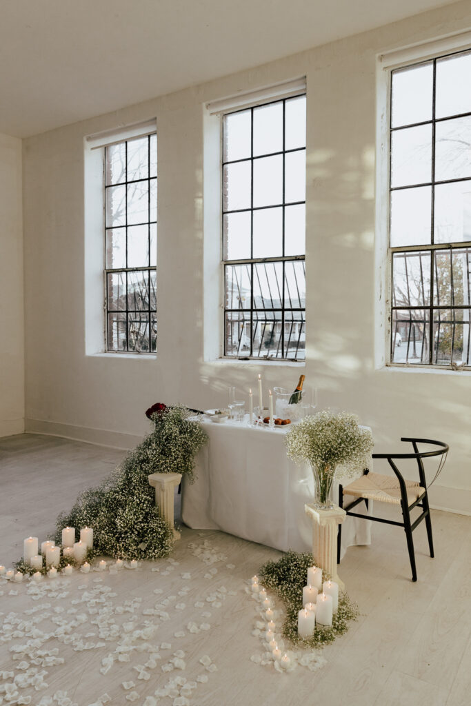 Details of an all white proposal set up, with baby&rsquo;s breath and candles at the Lumen Room studio in Fort Worth Texas.