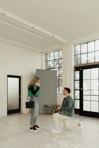 A couple in neutral attire at the Lumen Room Studio in Fort Worth, Texas get engaged surrounded by baby’s breath. Photography by Hannah Lylene Photography.