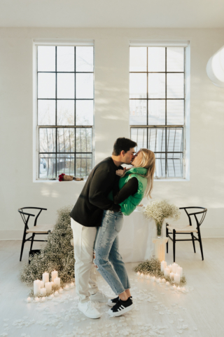 A couple in neutral attire at the Lumen Room Studio in Fort Worth, Texas get engaged surrounded by baby’s breath. Photography by Hannah Lylene Photography.