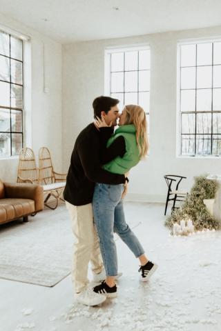 A couple in neutral attire at the Lumen Room Studio in Fort Worth, Texas get engaged surrounded by baby’s breath. Photography by Hannah Lylene Photography.