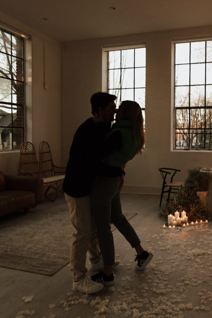 A couple in neutral attire at the Lumen Room Studio in Fort Worth, Texas get engaged surrounded by baby&rsquo;s breath. Photography by Hannah Lylene Photography.