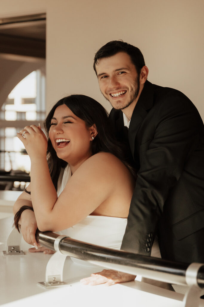 A couple in neutral attire at Bass Hall kiss and run around for engagement photos.