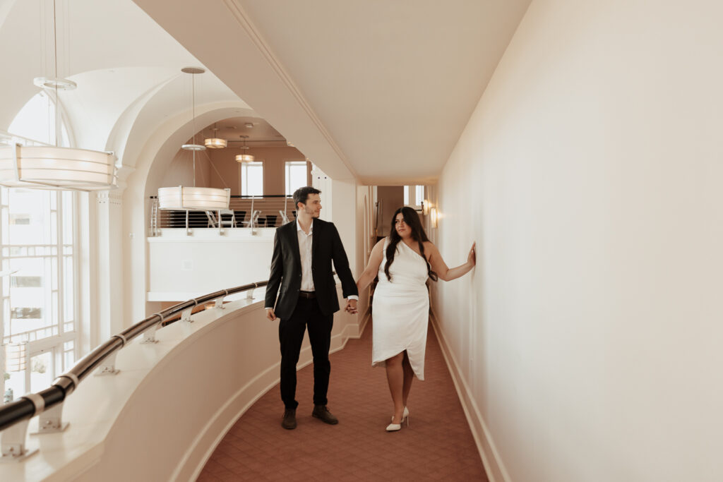 A couple in neutral attire at Bass Hall kiss and run around for engagement photos.