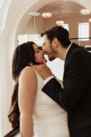 downtown-fort-worth-elopement-bass-hall A couple in neutral attire at Bass Hall kiss and run around for engagement photos.