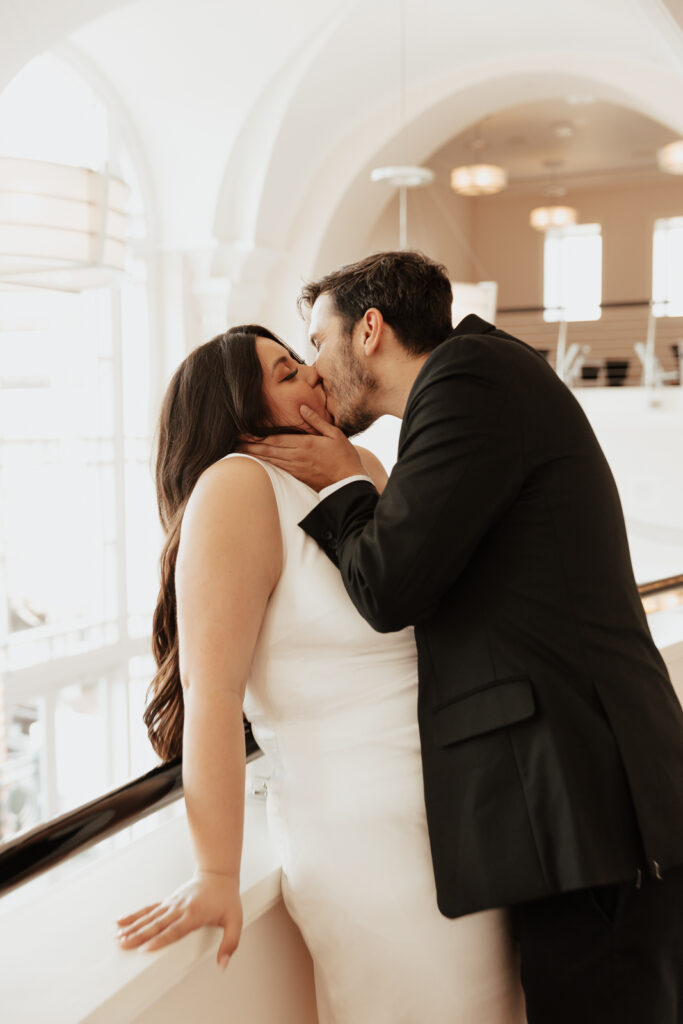 A couple in neutral attire at Bass Hall kiss and run around for engagement photos.