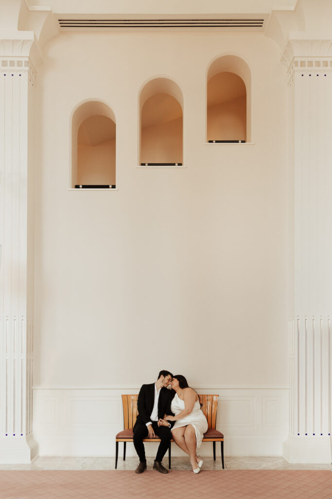 A couple in neutral attire at Bass Hall kiss and run around for engagement photos.