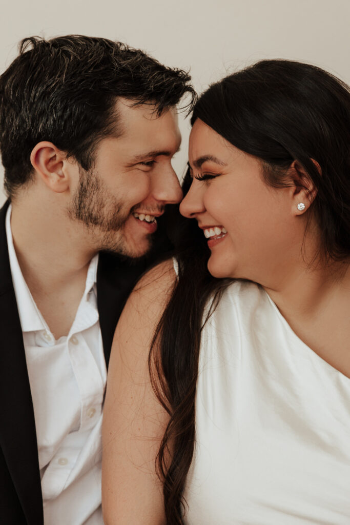 A couple in neutral attire at Bass Hall kiss and run around for engagement photos.