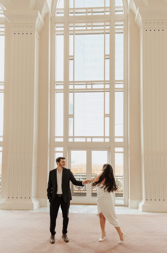 A couple in neutral attire at Bass Hall kiss and run around for engagement photos.