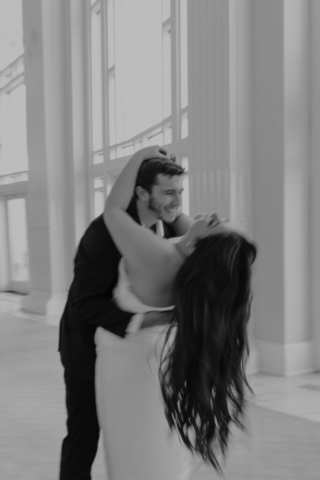 dfw-bw-city-hall-micro-wedding A couple in neutral attire at Bass Hall kiss and run around for engagement photos.