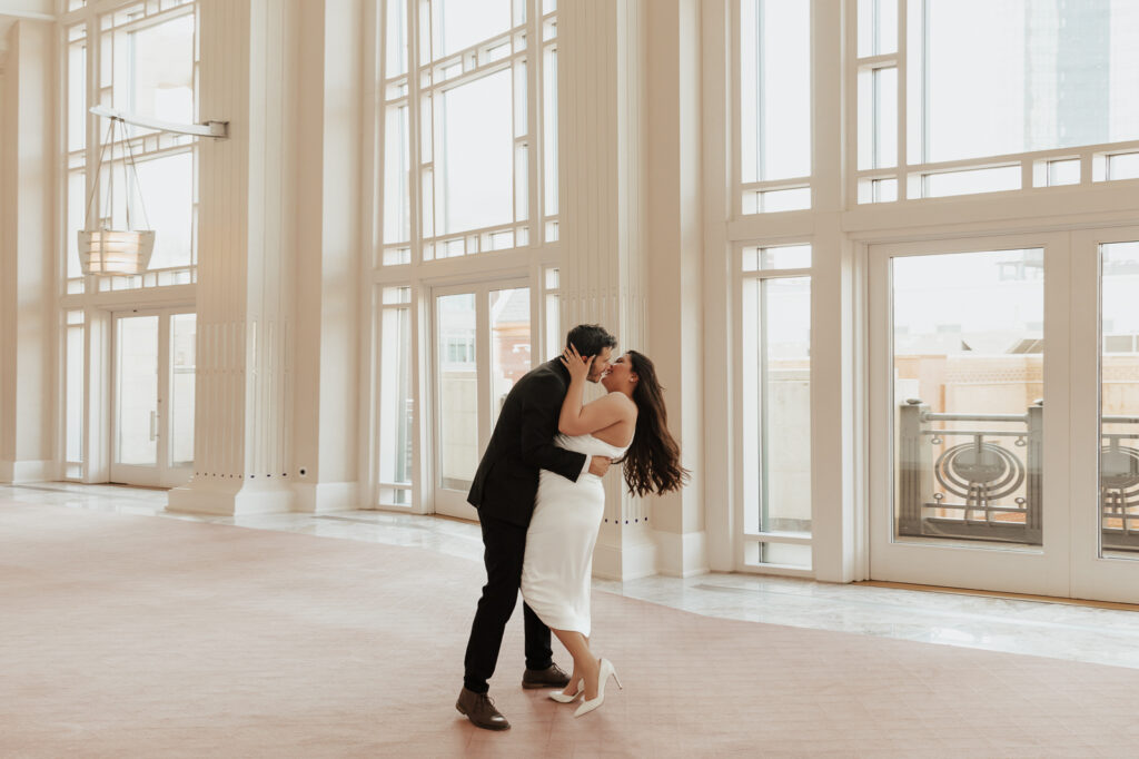 A couple in neutral attire at Bass Hall kiss and run around for engagement photos.