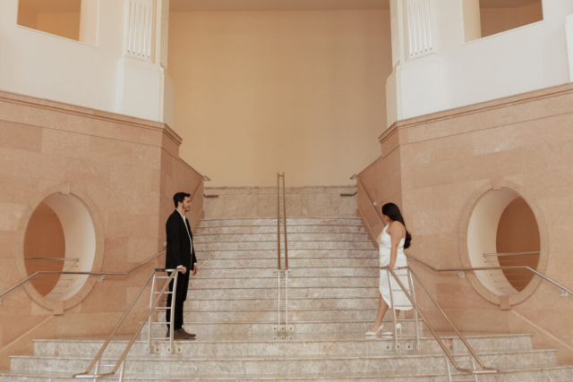 hannah-lylene-dfw-micro-wedding A couple in neutral attire in downtown Dallas Texas kiss and run around for engagement photos. Photography by Hannah Lylene Photography.