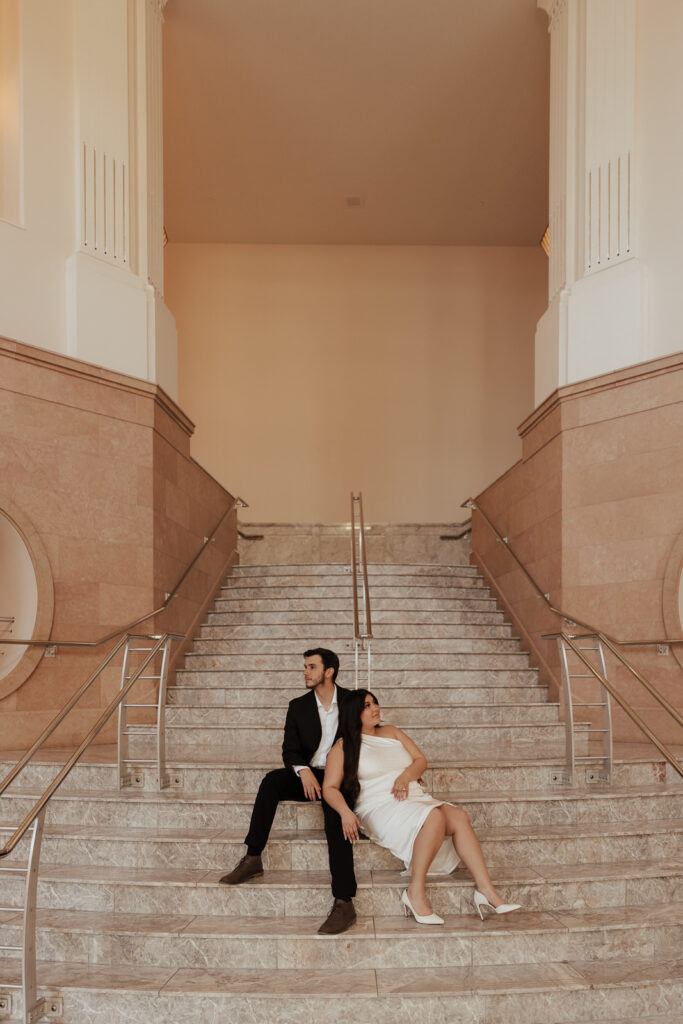 A couple in neutral attire in downtown Dallas Texas kiss and run around for engagement photos. Photography by Hannah Lylene Photography.