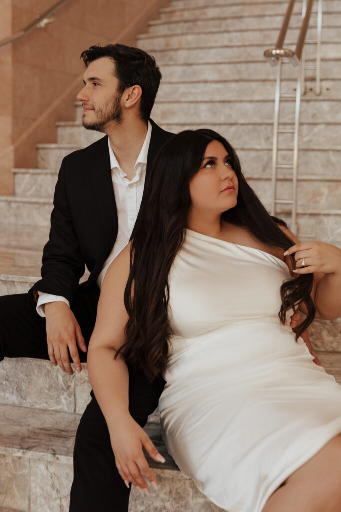 A couple in neutral attire in downtown Dallas Texas kiss and run around for engagement photos. Photography by Hannah Lylene Photography.