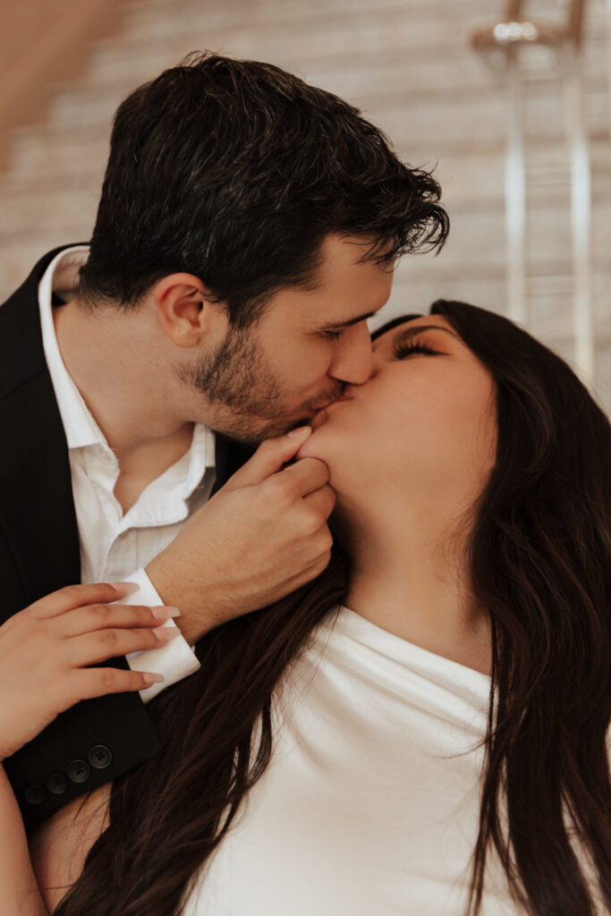 A couple in neutral attire in downtown Dallas Texas kiss and run around for engagement photos. Photography by Hannah Lylene Photography.