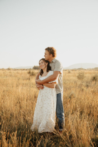 A couple in neutral attire run in an open field