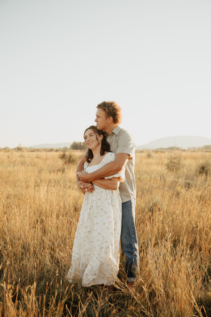 A couple in neutral attire run in an open field