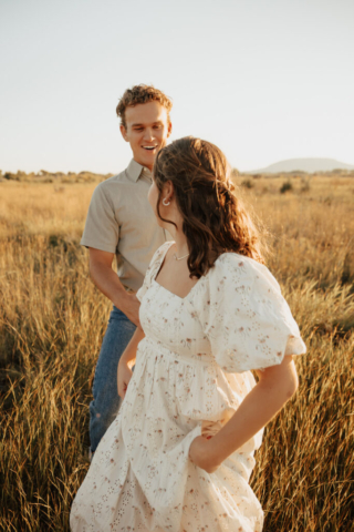 A couple in neutral attire run in an open field