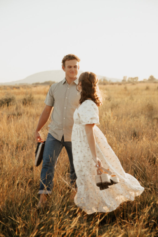 Young boy and girl walk through a golden field holding hands