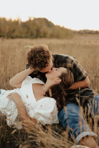 A young couple lay down in an open field