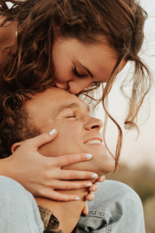 A young girl kisses a boys forehead