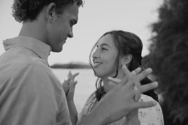 A young couple intertwines fingers nearby a lake