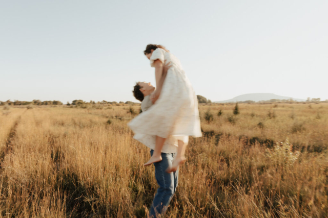 A young boy lifts a girl and spins her in the air