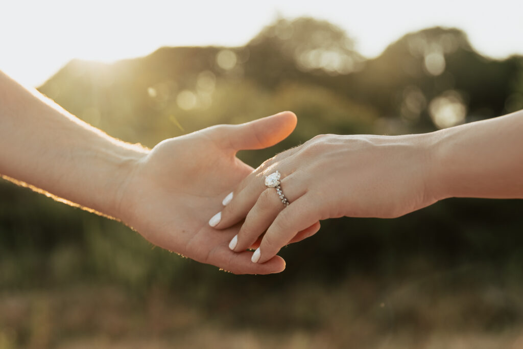 A couple in neutral attire at Grapevine Lake take candid engagement photos.
