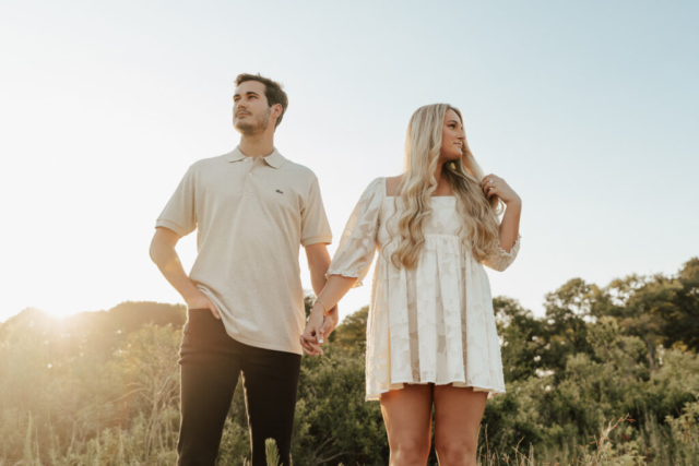 A couple in neutral attire at Grapevine Lake take candid engagement photos.