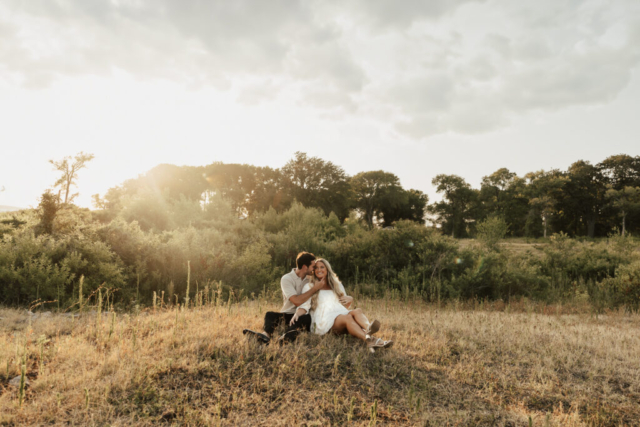 A couple in neutral attire at Grapevine Lake take candid engagement photos.