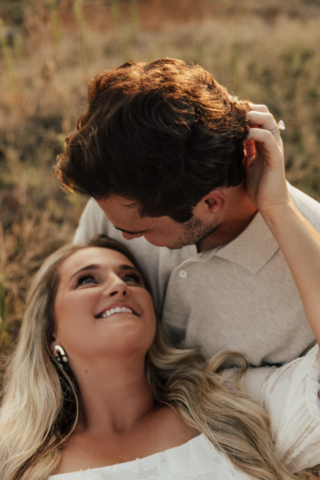 A couple in neutral attire at Grapevine Lake take candid engagement photos.