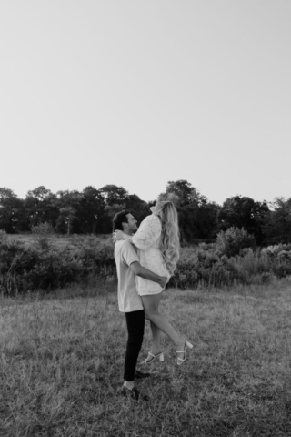 A couple in neutral attire at Grapevine Lake take candid engagement photos.