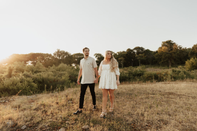 A couple in neutral attire at Grapevine Lake take candid engagement photos.