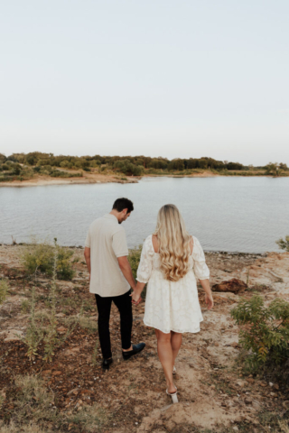 A couple in neutral attire at Grapevine Lake take candid engagement photos.
